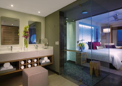 莫雷洛斯港Breathless Riviera Cancun Resort & Spa - Adults Only - All inclusive的一间带一张床的卧室和一间带镜子的浴室