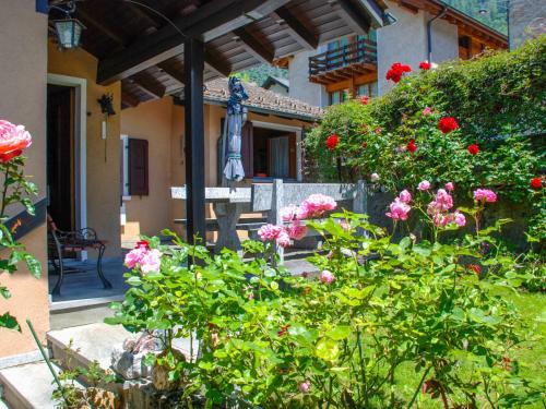 OlivoneHoliday Home La Casina by Interhome的一座花园,花园内种有粉红色的花卉,建筑前有雕像