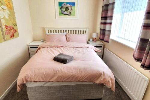 斯坦福德Stamford - Entire 1 bed cosy home.的一间卧室配有粉红色的床上用品和窗户