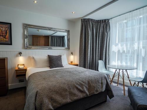 伊尔弗勒科姆卡尔顿酒店的一间卧室配有一张床、一张桌子和一面镜子