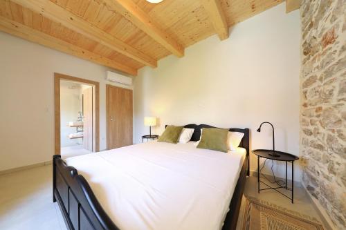 博扎瓦Villa Mira with a heated pool and a sea view的卧室配有一张白色的大床和石墙