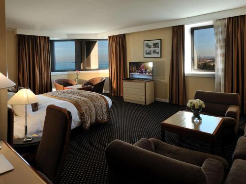 阿尔及尔Sofitel Algiers Hamma Garden的酒店客房配有床、椅子和电视。
