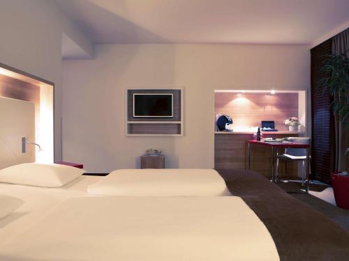 斯图加特美居斯图加特机场展览会酒店的配有一张床和一张书桌的酒店客房