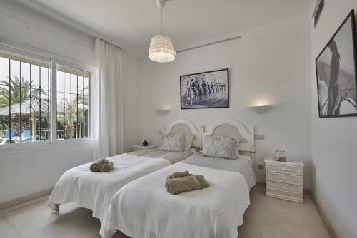 EsteponaVilla Pinsapo的白色卧室配有两张带毛巾的床