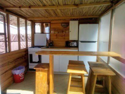 阿尔加罗沃Eldorado Yurt的厨房配有桌子、两把凳子和冰箱。