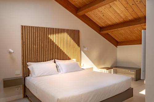 SantʼOmeroVilla Corallo的卧室配有一张白色大床和木制床头板