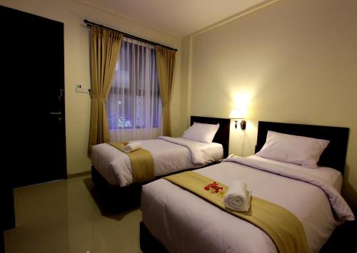 库塔芒加尔印尼酒店的配有窗户的酒店客房内的两张床