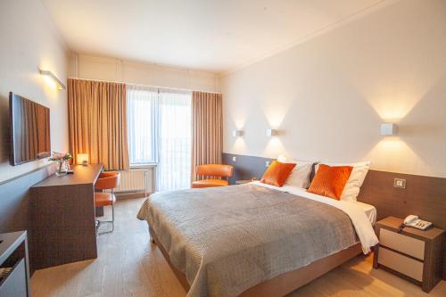 泽布吕赫Hotel Monaco Zeebrugge Beach的酒店客房设有一张大床和一张书桌。