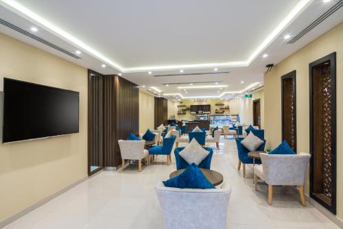 利雅德Myrtle Hotel - Al Sahafa的一间设有蓝色椅子和平面电视的等候室