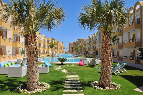 苏塞Appartement S 1 résidence les Dunes sousse avec piscine的两棵棕榈树,在一座建筑前面的院子