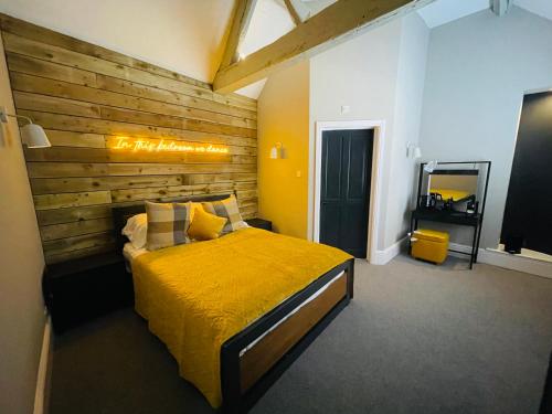 斯托尔河畔希普斯顿The Lazy Pug的一间卧室设有一张黄色的床和木墙