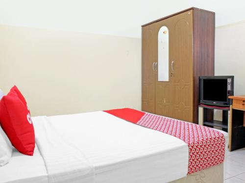 帕朗卡拉亚Capital O 90417 Hotel Batu Suli Internasional的一间卧室配有一张带红色枕头的床和一台电视。