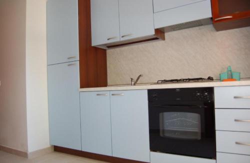 Isca sullo IonioMIMOSA CAMPING的厨房配有白色橱柜和黑烤箱。
