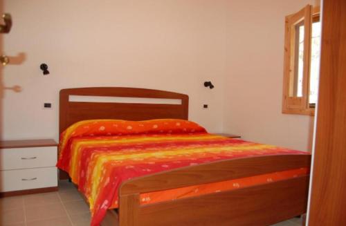 Isca sullo IonioMIMOSA CAMPING的一间卧室配有一张带橙色棉被的木床