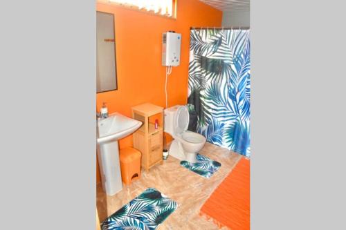 提克豪Hiti Tikehau, the ocean side bungalow的浴室设有橙色的墙壁、卫生间和水槽。