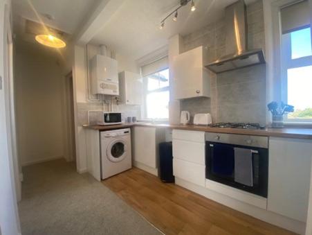 曼斯利Coastal Corner的厨房配有白色橱柜、洗衣机和烘干机