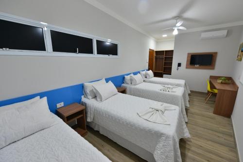 伊帕廷加Vinds Economic Hotel的酒店客房设有两张床和一张桌子。