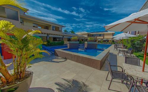 塞古罗港Safira Praia Hotel的一个带游泳池、椅子和遮阳伞的庭院