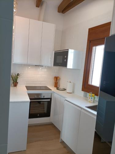 厄尔·坎皮洛·德·罗达尔Casa Redondo的白色的厨房配有白色的橱柜和微波炉