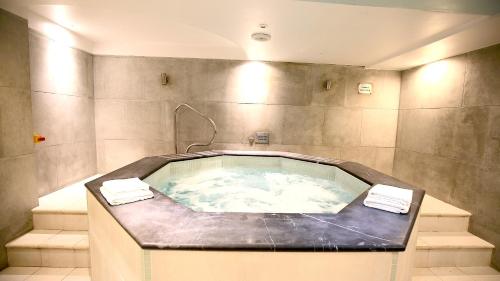 伦敦Roland House Apartments的浴室设有按摩浴缸和2条毛巾