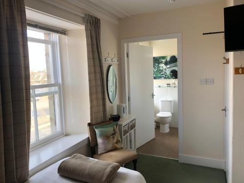 TarvesThe Aberdeen Arms Hotel的一间卧室设有窗户、椅子和卫生间