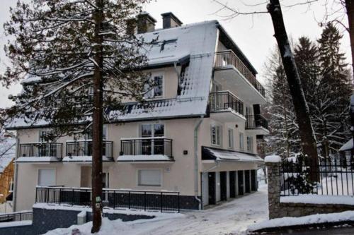 斯克拉斯卡波伦巴Apartament Oliwkowy的一座白色的大建筑,有雪