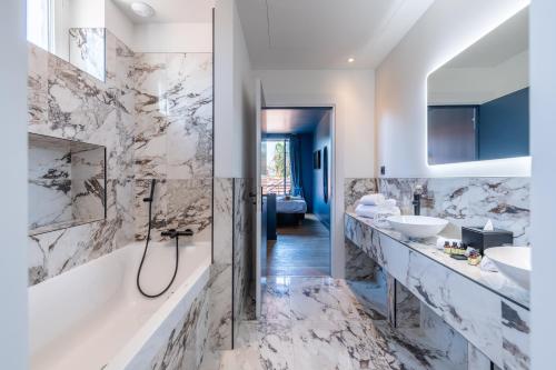 尼斯Boutique Hotel Nice Côte d'azur的浴室配有2个盥洗盆、浴缸和淋浴。