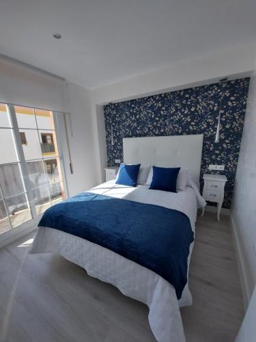 马拉加Ático Chill Out la Biznaga的一间卧室配有一张带蓝色床单的大床和窗户。