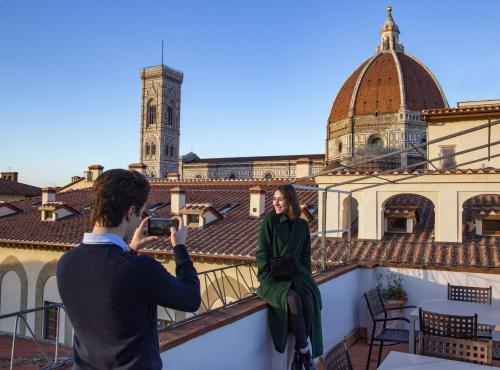 佛罗伦萨Boutique Hotel del Corso的把女人的照片放在阳台上的男人