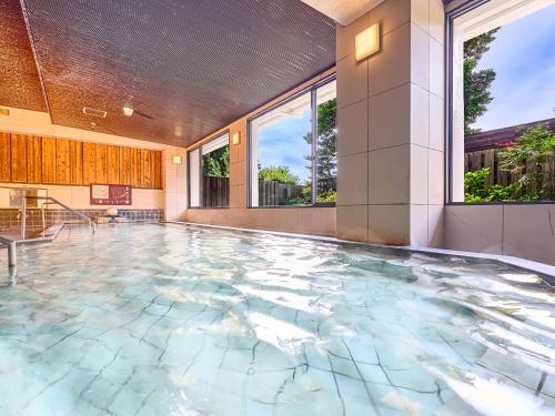 志摩市Yukai Resort Premium Shima Saichoraku的室内游泳池,设有瓷砖地板和窗户