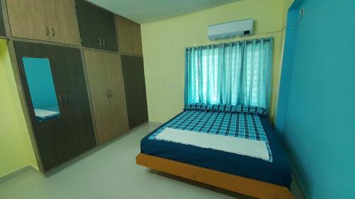 蒂鲁帕蒂Tirupati Homestay - 2BHK AC Family Apartments near Alipiri and Kapilatheertham - Walk to A2B Veg Restaurant - Super fast WiFi - Android TV - 250 Jio Channels - Easy access to Tirumala的一间卧室配有一张床、一个窗口和橱柜