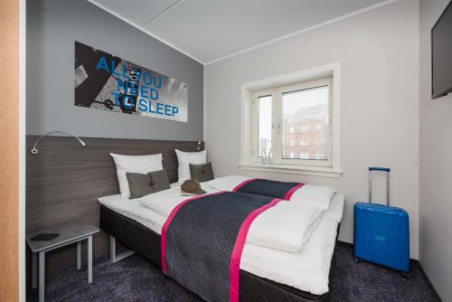 欧登塞欧登塞卡宾酒店的一间卧室配有一张大床和一个蓝色的行李箱