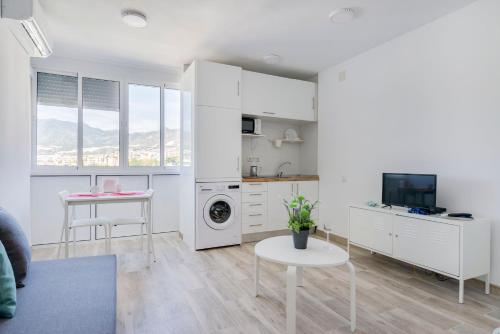 贝纳尔马德纳Panoramic views cosy studio的厨房配有白色橱柜、桌子和电视。