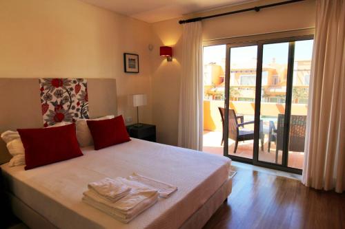 斯代塔维拉Anis Lux Tavira Residence Villa 5M的一间卧室配有一张带红色枕头的床和一个阳台