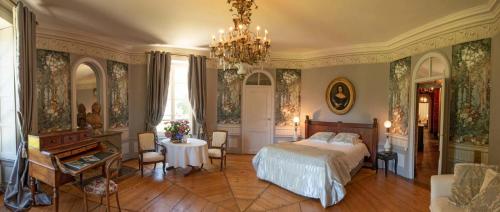 SyamLa Villa Palladienne - Château de Syam的一间卧室配有一张床、一张桌子和一个吊灯。
