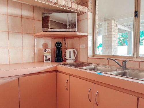 卡那封Carnarvon 3BR & 2BA Holiday House的厨房配有橙色橱柜、水槽和窗户。