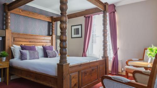 沃克索普姆图克伦伯公园Spa酒店的一间卧室配有一张带紫色枕头的木制天蓬床