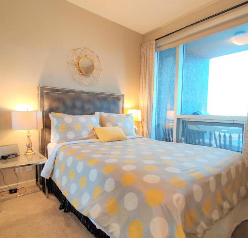 卡尔加里莫金迪行政套房公寓 - 荷尔露的一间卧室配有一张带波卡圆点床单的床和窗户。