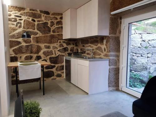 TravassosCasa do Doutor Palheiro的厨房设有石墙和白色橱柜