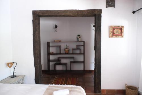 卡萨雷斯The Wild Olive Andalucía Agave Guestroom的一间卧室设有一张床铺和书架的开放式门廊