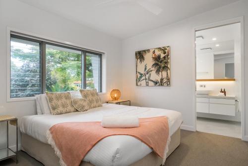 拜伦湾Foam的白色卧室配有一张带橙色毯子的大床