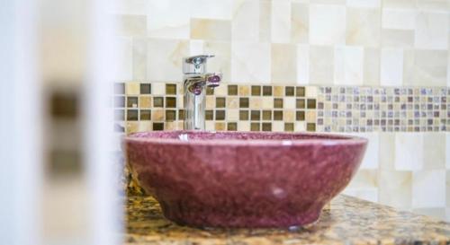 金斯敦Royal Bliss Apartment Suites的浴室内带水龙头的紫色水槽