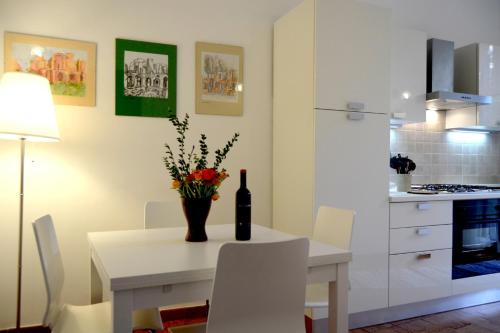 罗马圣彼得大教堂伊尔利莫度假屋的白色的厨房配有一张桌子和一瓶葡萄酒