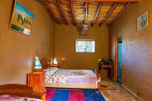 Aït Boukha游牧住宿加早餐旅馆的一间卧室配有一张床、一张桌子和一个窗户。