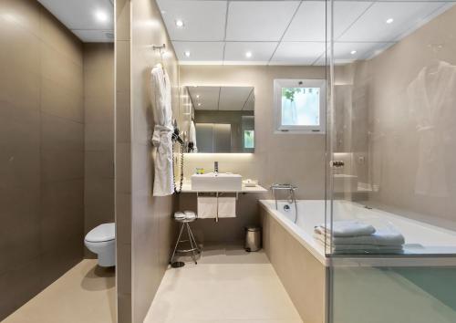 托雷利亚诺槟榔树酒店的带浴缸、盥洗盆和卫生间的浴室
