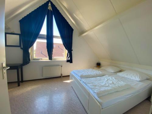 布雷斯肯斯Hello Zeeland - Vakantiehuis Zwin 172的一间卧室配有一张带蓝色窗帘的床和一扇窗户