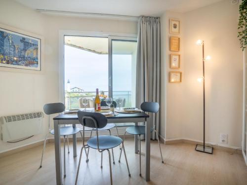 比亚里茨瑞斯海湾比亚里茨公寓的一间带桌椅和窗户的用餐室