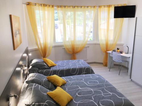 卢尔德Appartement Le Solea 100m2 climatisé parking proche Sanctuaires的配有黄色窗帘的客房内的两张床