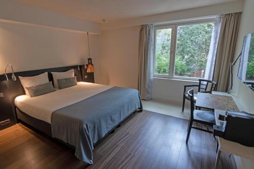 多尔恩Hotel Landgoed Zonheuvel的一间卧室配有一张床、一张书桌和一个窗户。