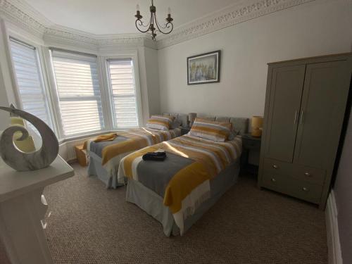 伊斯特布恩Penhale Holiday Flats的一间卧室配有三张床和吊灯。